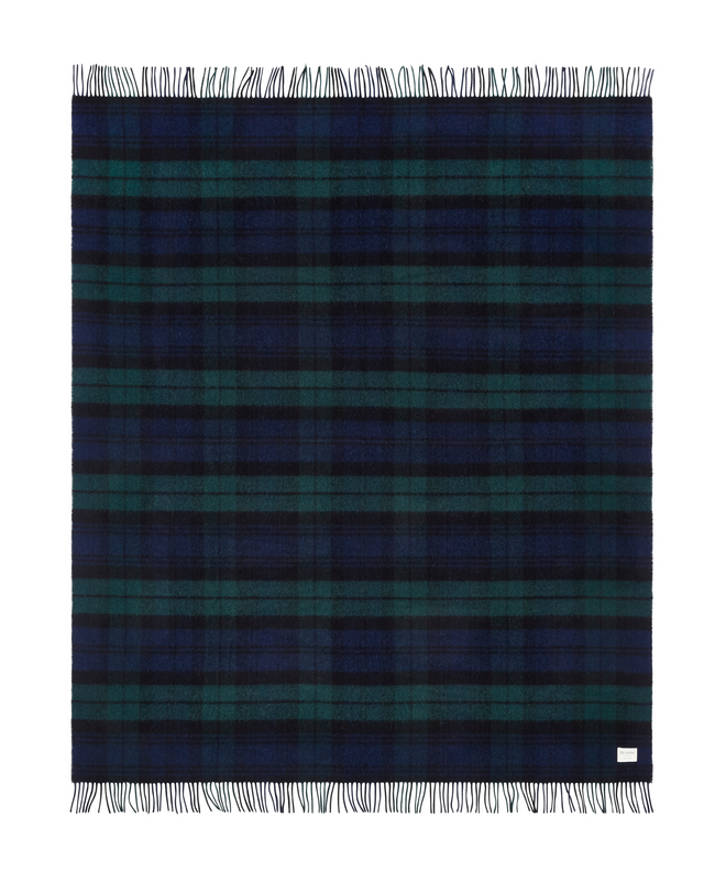 Flatlay image of a wool blanket folded into a small rectangle, the edge of the blanket is fringed, the blanket is multi-coloured check with alternating shades of dark red, faded red, navy, faded navy and cream. Image of the blanket laid out flat with fringing on both edges.