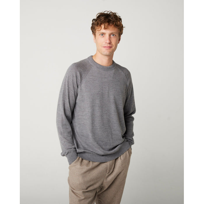 A flatlay image  of a grey crew neck jumper. The jumper has a fine knit with a ribbed hem, cuff and neckline. The jumper has full length sleeves.  A close up photo of a male model wearing the grey jumper. The jumper has a line of spotting detail running from the neck to the pit of the jumper. 