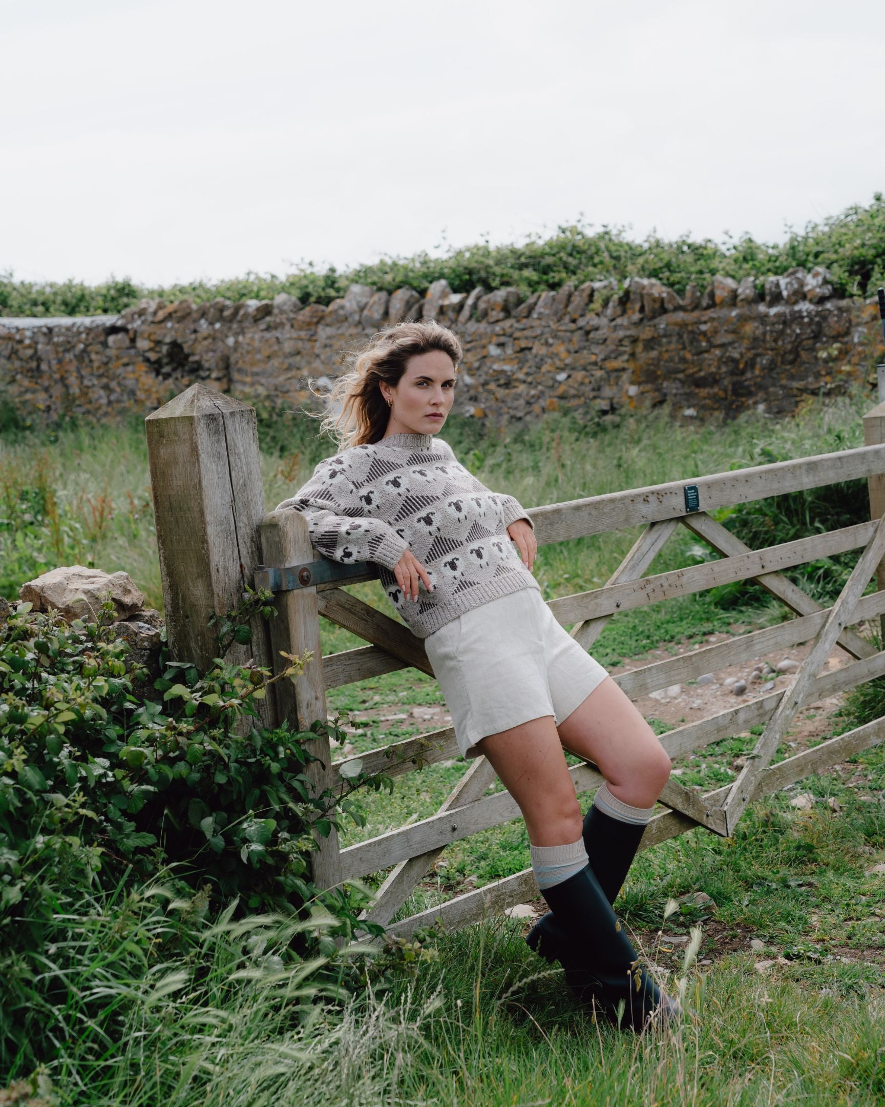 Woman sitting on a wooden gate in a rural setting